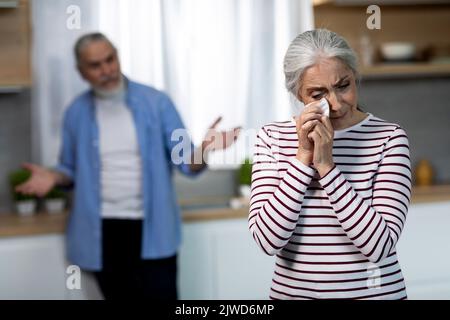 Depressed Senior Woman Crying In Kitchen During Argue With Husband Stock Photo