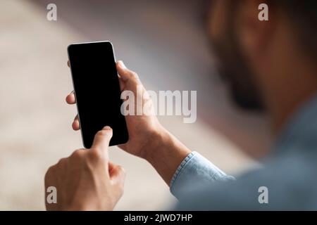Unrecognizable Black Man Using Smartphone With Blank Indoors, Mockup Stock Photo