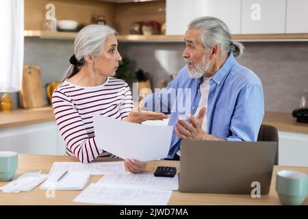 Worried Elderly Spouses Checking Financial Documents In Kitchen At Home Stock Photo