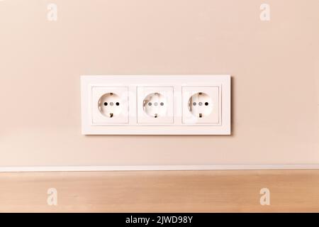 Group of white european electrical outlets on modern neutral beige wall Stock Photo
