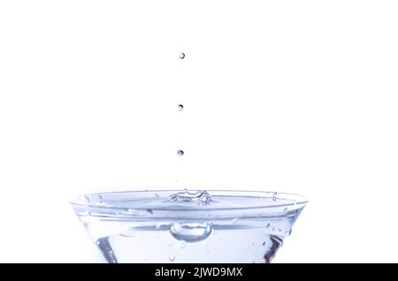 Close-up of water drop falling into a glass on white background Stock Photo