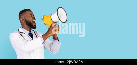 Medical News. Angry black male doctor in uniform screaming with megaphone Stock Photo