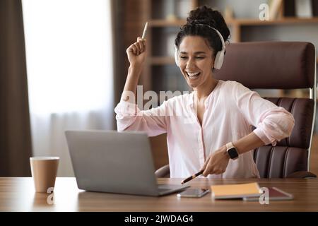 Emotional young woman entrepreneur celebrating success, office interior Stock Photo