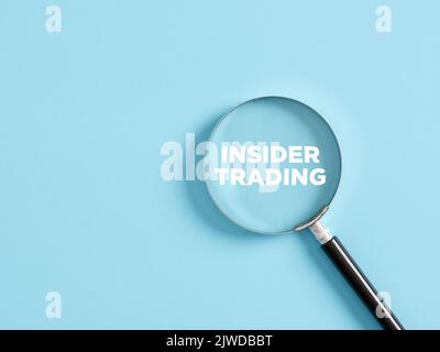 Magnifier with the text insider trading on blue background. Business concept. Stock Photo