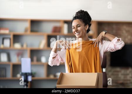 Happy woman unpacking delivery box and recording video Stock Photo