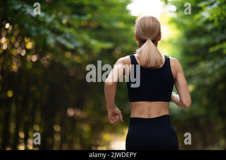 Back view of woman in sportswear jogging in park Stock Photo