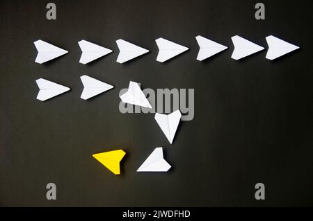 Yellow paper plane origami leading white planes on dark background. Leadership skills concept. Stock Photo