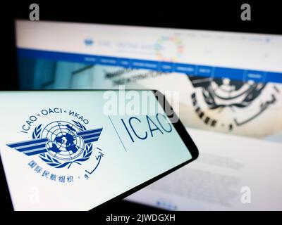 Mobile phone with logo of International Civil Aviation Organization (ICAO) on screen in front of website. Focus on center-left of phone display. Stock Photo