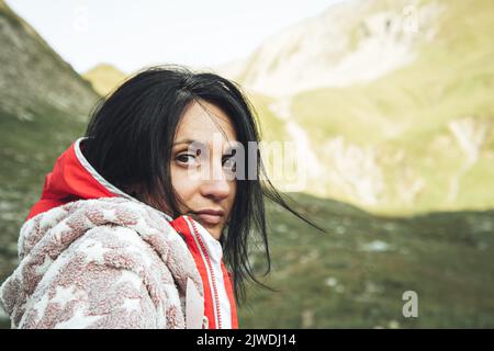 Close up of caucasian woman face looking straight with cozy pajama and blue sleeping bag on top in nature with sun in the background. Challenge and wo Stock Photo