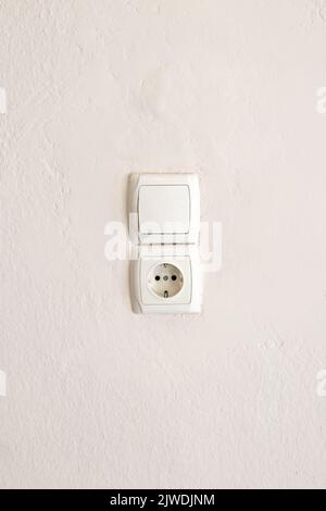 Socket and light switch isolated on white wall background. Electrical   socket and light switch. White plastic power outlet. No people, Copy space. Stock Photo