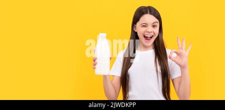 winking child hold dairy beverage product. teen girl going to drink milk. Horizontal poster of isolated child face, banner header, copy space. Stock Photo