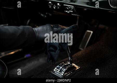 Employee of a car wash or a car detailing studio cleans the gear lever  Stock Photo