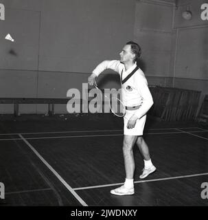 1965, historical, scottish male badminton player on court hitting a shuttlecock, Scotland, UK. Thistle logo on his v-neck sweater and wearing shorts and the traditional plimsolls, the common sports shoes of the era. Stock Photo