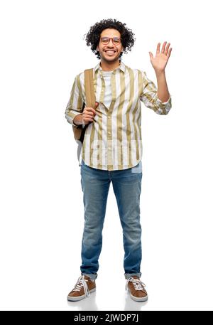Happy student with backpack waving hand while jumping on blue ...