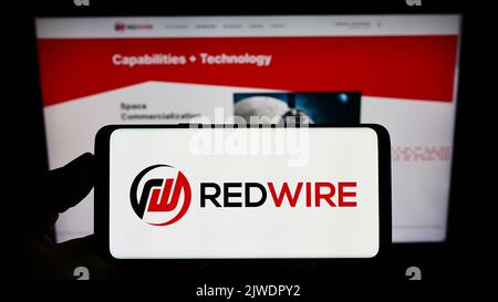 Person holding smartphone with logo of US aerospace company Redwire Corporation on screen in front of website. Focus on phone display. Stock Photo