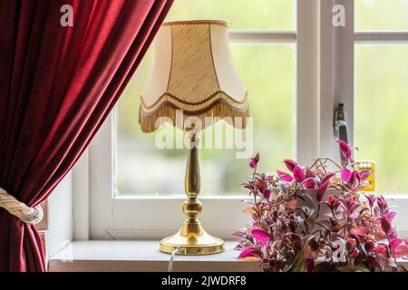 Bouquet of red flowers with old vintage lamp on the windowsill Stock Photo