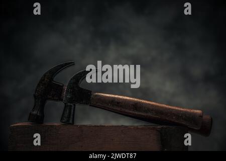 concept of craftsmanship and handwork illustrated by set of two carpentry hammers on top of old rustic wooden workbench Stock Photo
