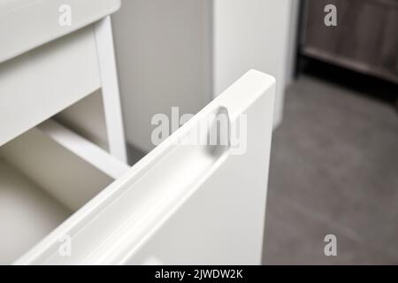 Solution for placing kitchen utensils in modern kitchen - horizontal sliding pull out plastic drawer shelves storage with handle closeup in cupboard Stock Photo