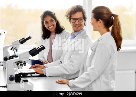 scientists with microscopes working in laboratory Stock Photo