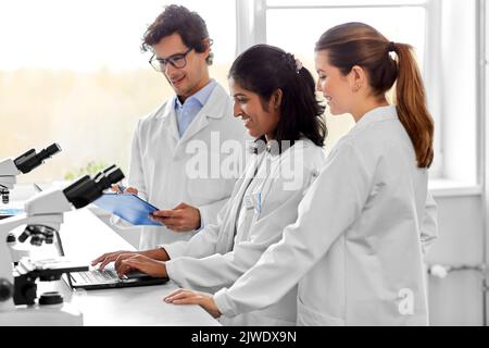 scientists with microscopes working in laboratory Stock Photo