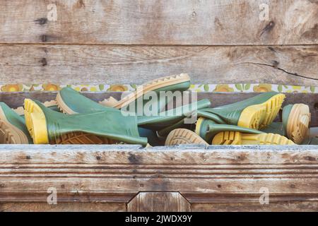 Wooden box filled with new green rubber rain boots Stock Photo