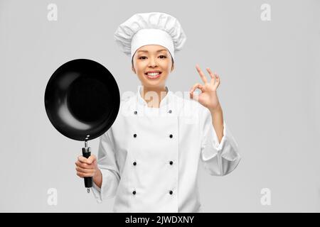 smiling female chef with frying pan showing ok Stock Photo