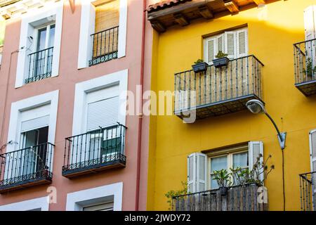 Yellow pink facades of residential apartment buildings houses in classical style. Balconies with plants, panoramic windows, doors with wooden shutters Stock Photo