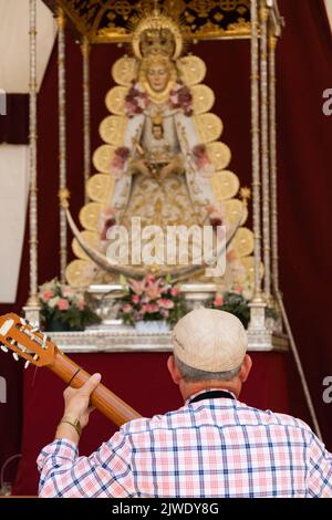 Barcelona, Catalonia, Spain, July 4, 2022:Description: The Virgin of El Rocio on a red altar with golden ornaments with a man playing guitar in the fr Stock Photo