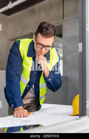 male architect with blueprint working at office Stock Photo