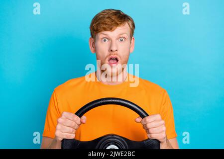 Photo of impressed ginger hair guy drive car wear orange t-shirt isolated on teal color background Stock Photo