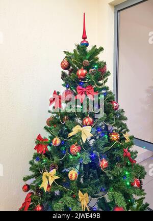 Interior of a room with a Christmas tree decorated with bows, sparkling glass balls and Christmas toys. Stock Photo