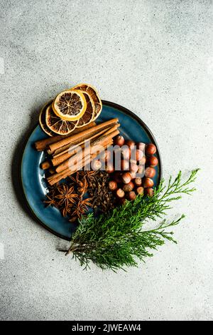 Overhead view of cinnamon sticks, star anise, hazelnuts, cloves, dried orange slices and thuja branches Stock Photo