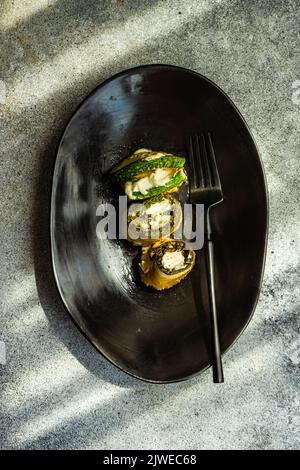 Overhead view of a plate of roasted courgette rolls filled with cream cheese Stock Photo