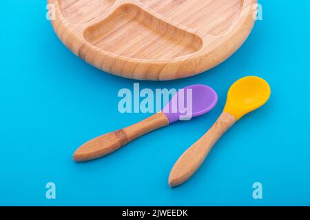 Wooden bowl. Bamboo plate with spoon isolated on blue background Stock Photo