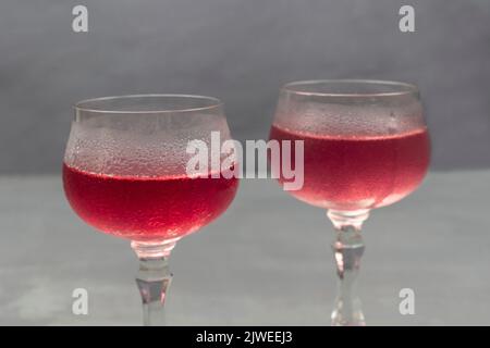 Two wine glasses with cooling drink. Drops of water on misted glass of wine glass. Close up.  Grey background Stock Photo