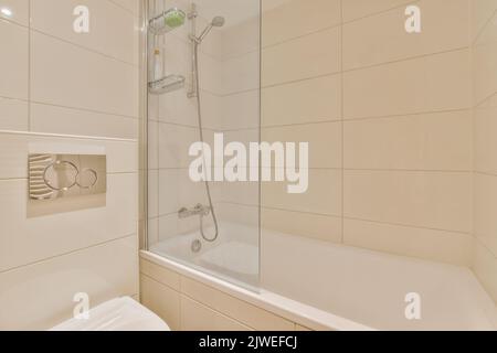 Flush toilet and shower cabin with glass partition and curtain located near sink and shelf with cosmetic products in washroom at home Stock Photo