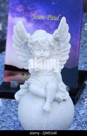 Statuette d'un ange sur une pierre tombale offrant une rose. Saint-Gervais-les-Bains. Haute-Savoie. Auvergne-Rhône-Alpes. France. Europe. Stock Photo