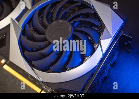 Gpu graphics card fan top view. Cooler fan close-up in bright blue light on black, PC hardware details. Components from computer cooling system with s Stock Photo