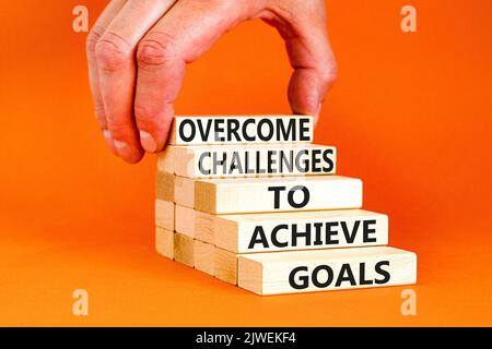 Overcome challenges to achieve goals symbol. Concept words Overcome challenges to achieve goals on wooden blocks on a beautiful orange background. Bus Stock Photo