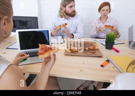 Diverse business team people workers eating pizza together at workplace, friendly multi-ethnic colleagues group talking enjoying having fun and corpor Stock Photo