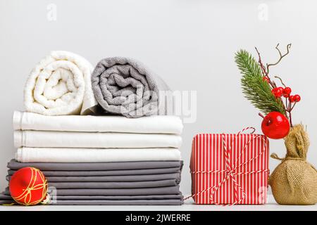 Stack of bed linen, bed sheet and folded rolls of towels on a table with Christmas decor Stock Photo