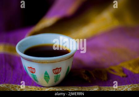 An authentic Ethiopian coffee cup, on a hand-knitted scarf, dyed by a purple herbal dye, made of the Flamingia Grahamiana plant, grown up in Ethiopia Stock Photo