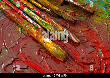 Close up on grungy paint brushes on messy artist canvas covered with oil paints conceptual representation for fine art gallery, visual artistic genius Stock Photo