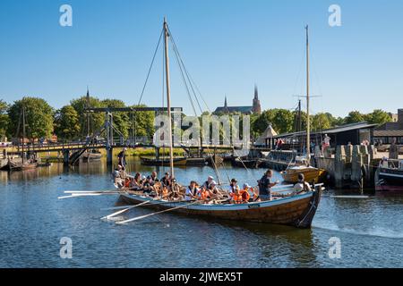 Replica viking ship rowing back in to the Viking Ship Museum with gothic cathedral behind, Roskilde, Zealand, Denmark, Europe Stock Photo
