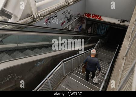 Bucharest, Romania - September 3, 2022: Senior man walks down a dark, dirty and vandalised stairway in Bucharest. Stock Photo
