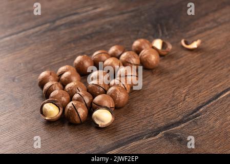 Selective focus on macadamia nuts over wooden background. Focus on the front of the nuts. The back of the nuts is blurred. Copy space. Stock Photo
