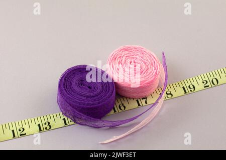 Rolls of pink and purple lace ribbons and measuring tape Stock Photo