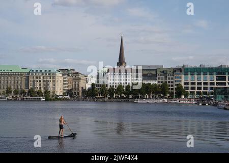 Man standing on a stand up paddle board is paddling on Binnenalster in Hamburg. Stock Photo