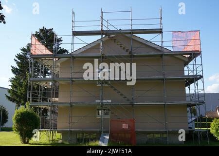 Residential apartment house in Switzerland with scaffolding and protective net, for reconstruction and installation of insulation. Stock Photo