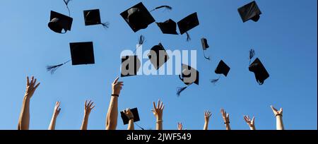 Graduation Caps Thrown in the Air on blue sky Stock Photo